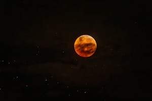 Photo by Tom Fisk - Telugu Word Capture of a vivid blood moon with stars in a dark night sky.